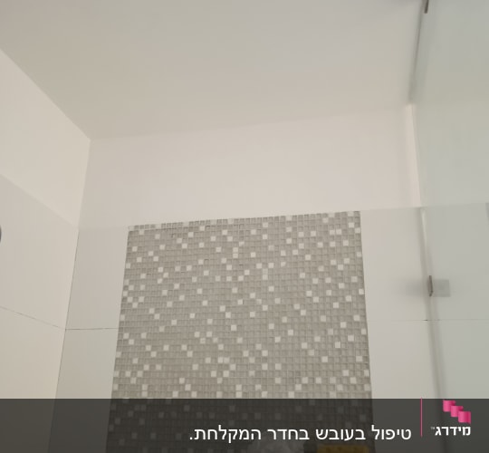ספוג צהוב על מדף במקלחת עם אריחים קטנים